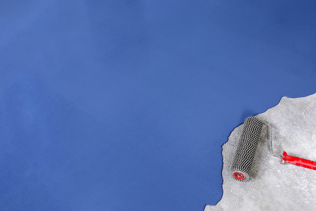 Mavi renkte yeni boyanmış oto yıkama zemini ve bir boya rulosu.